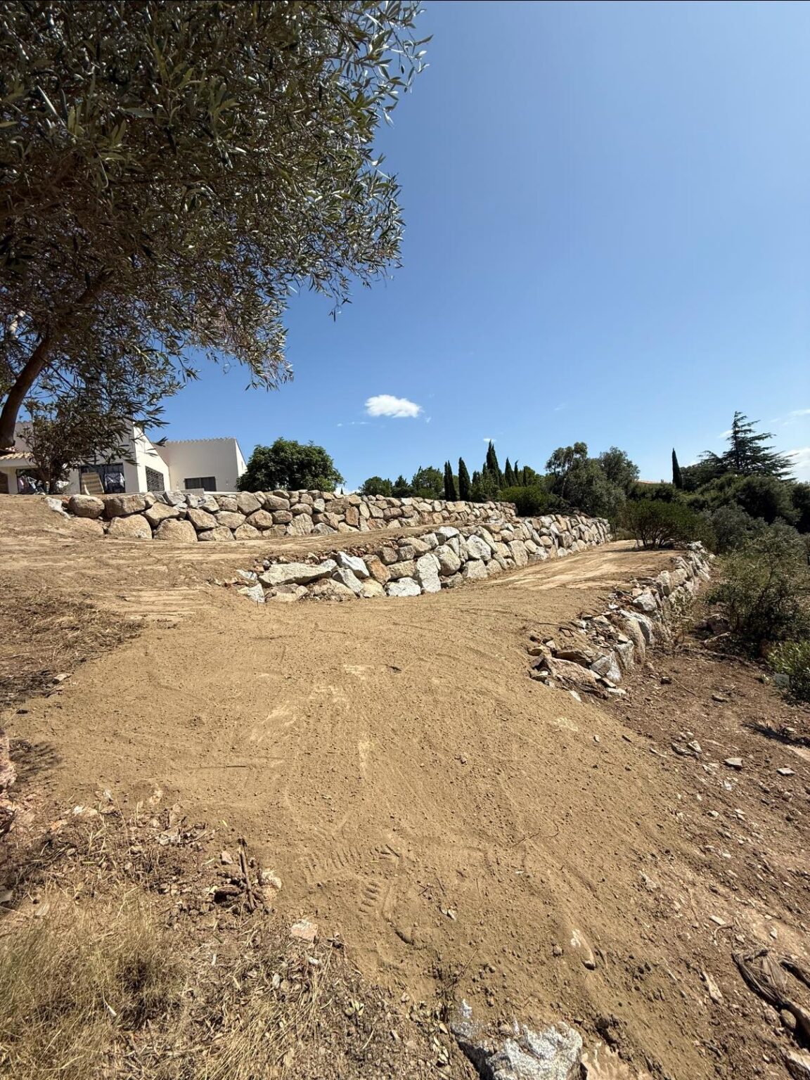 Création de paliers en enrochement pour structurer le terrain et lui donner du relief - Apport de terre végétale sur l’ensemble du jardin, prêt à être végétalisé.