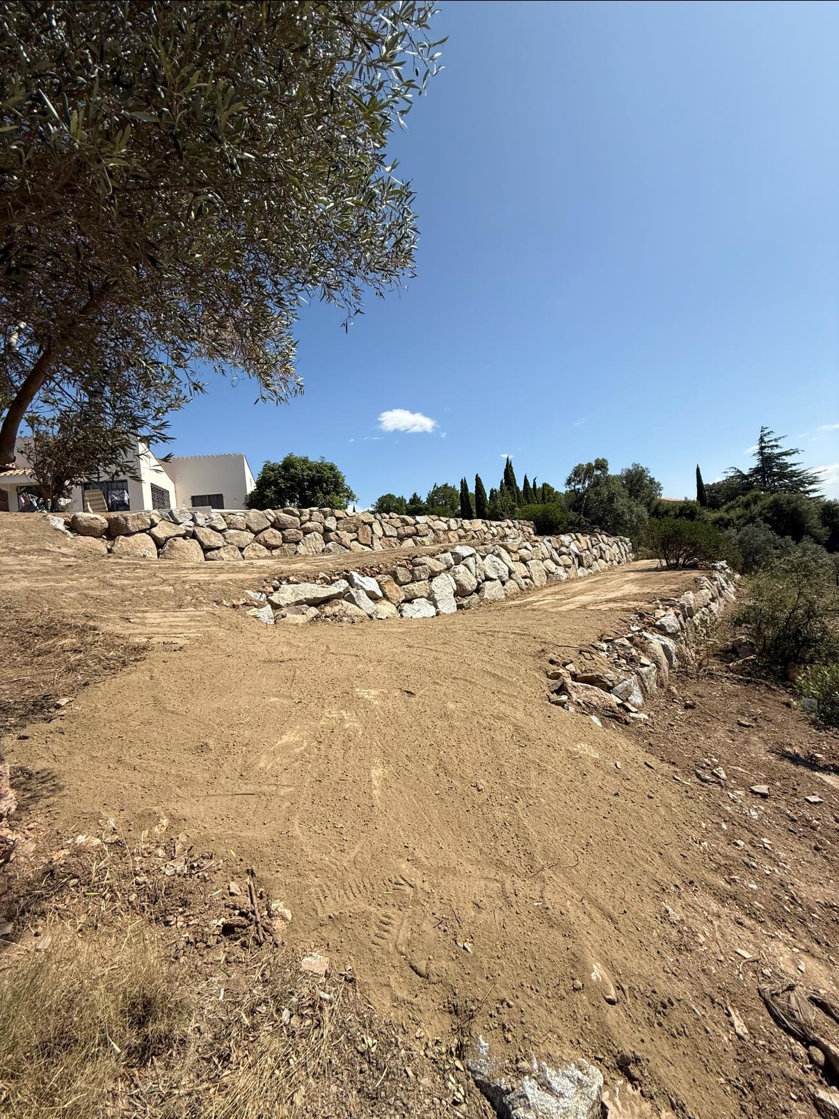 Création de paliers en enrochement pour structurer le terrain et lui donner du relief - Apport de terre végétale sur l’ensemble du jardin, prêt à être végétalisé.