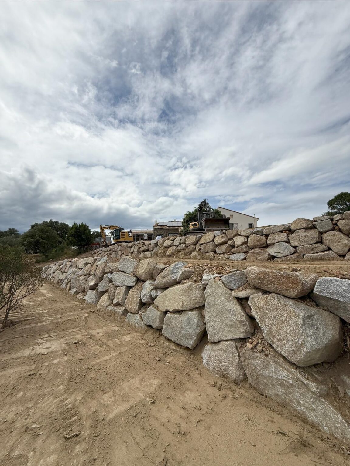 Création de paliers en enrochement pour structurer le terrain et lui donner du relief - Apport de terre végétale sur l’ensemble du jardin, prêt à être végétalisé.