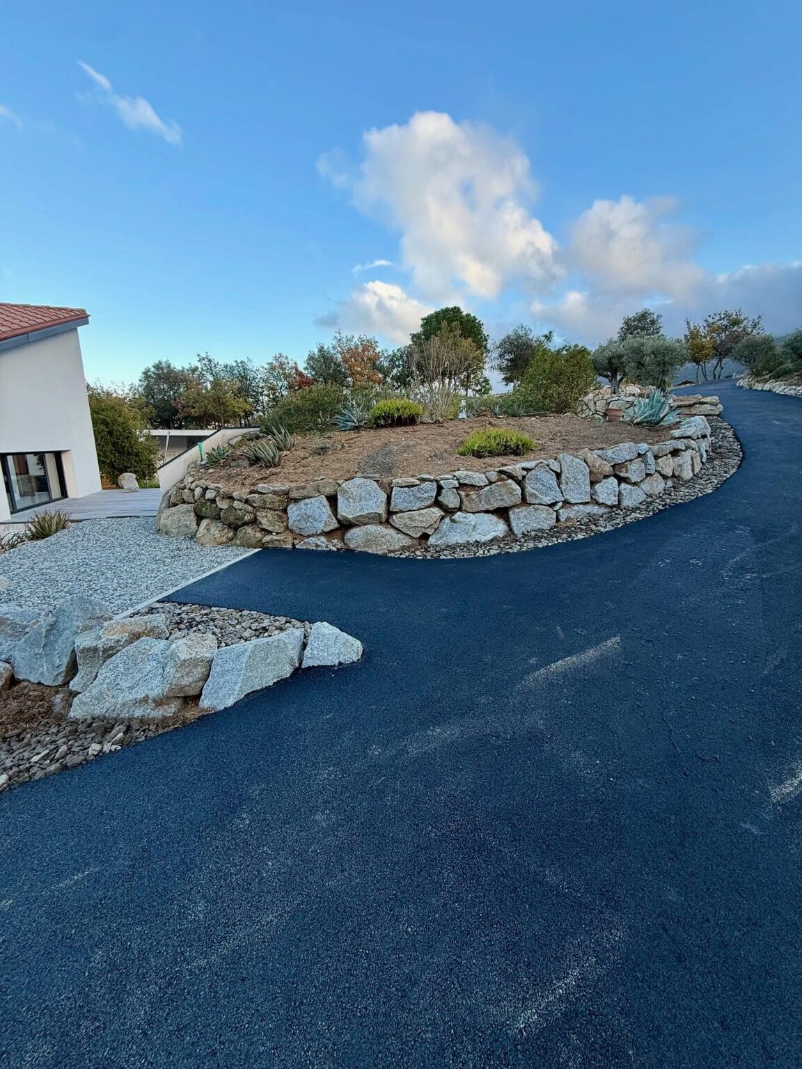 Chantier à Villelongue dels Monts : enrochement de type granite, réalisation d’un accès en enrobé avec bordures en schiste concassé, et création d’une aire de retournement en gravier granitique au fond de la parcelle.