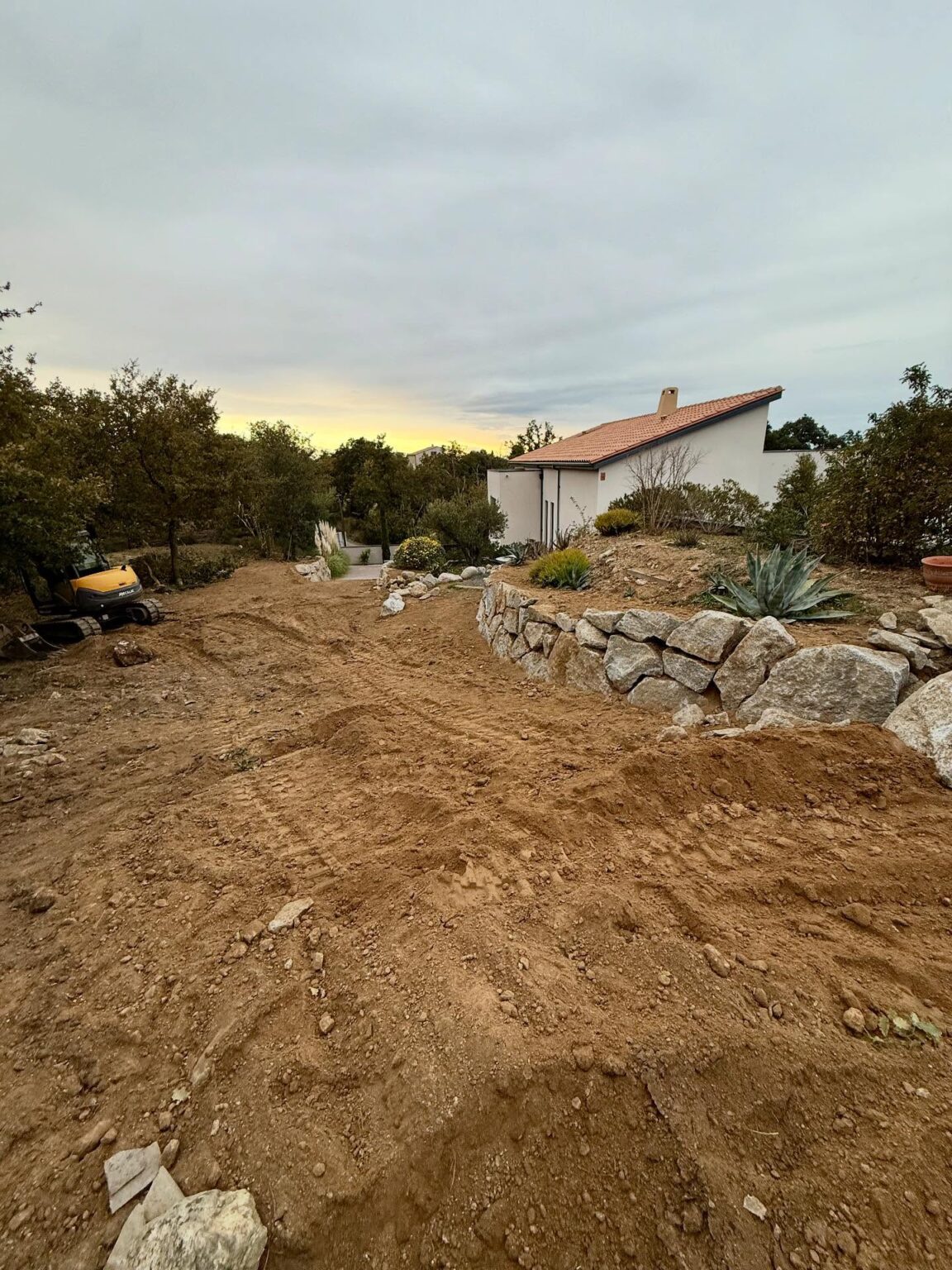 Chantier à Villelongue dels Monts : enrochement de type granite, réalisation d’un accès en enrobé avec bordures en schiste concassé, et création d’une aire de retournement en gravier granitique au fond de la parcelle.