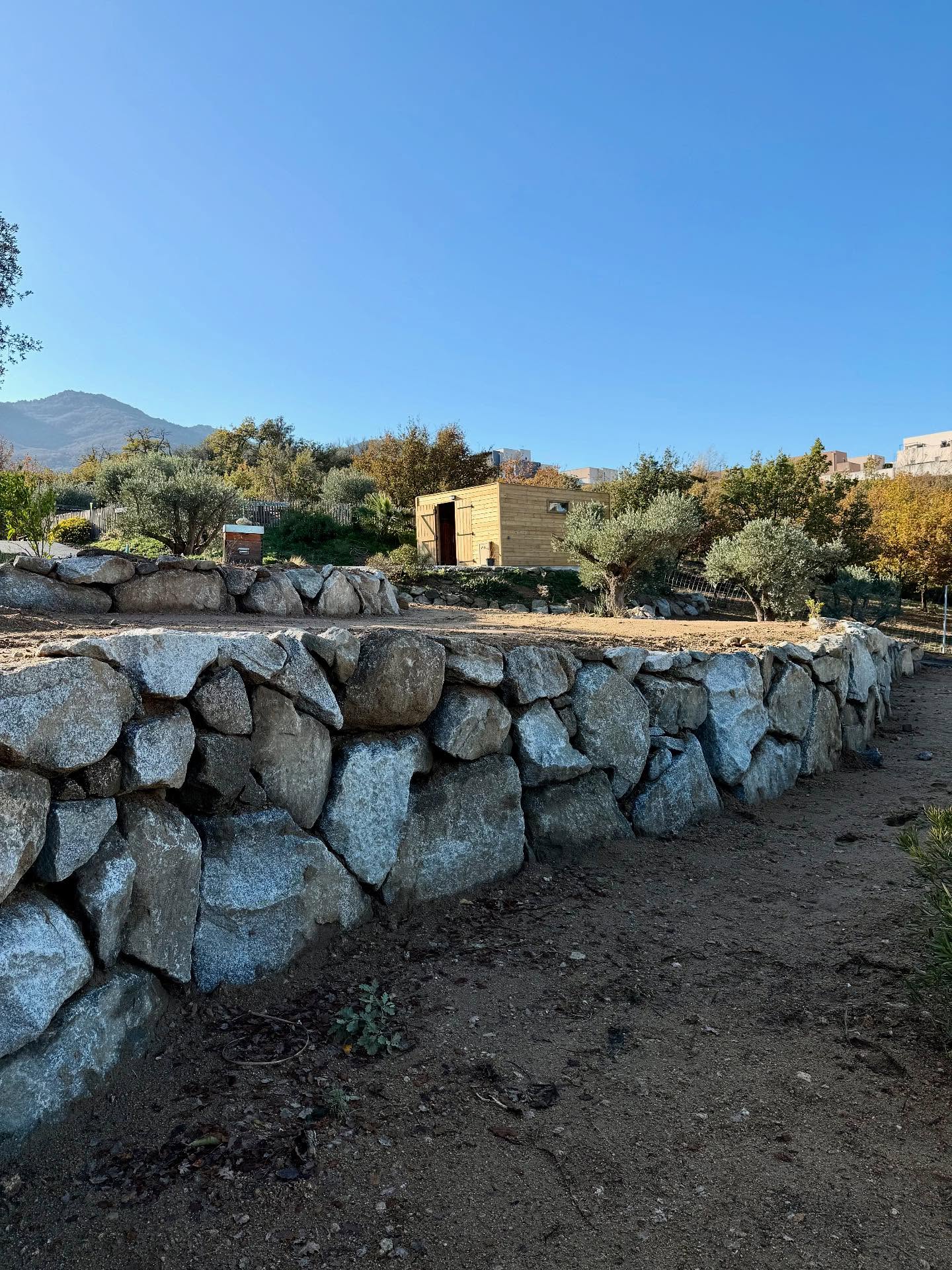 Chantier à Villelongue dels Monts : enrochement de type granite, réalisation d’un accès en enrobé avec bordures en schiste concassé, et création d’une aire de retournement en gravier granitique au fond de la parcelle.