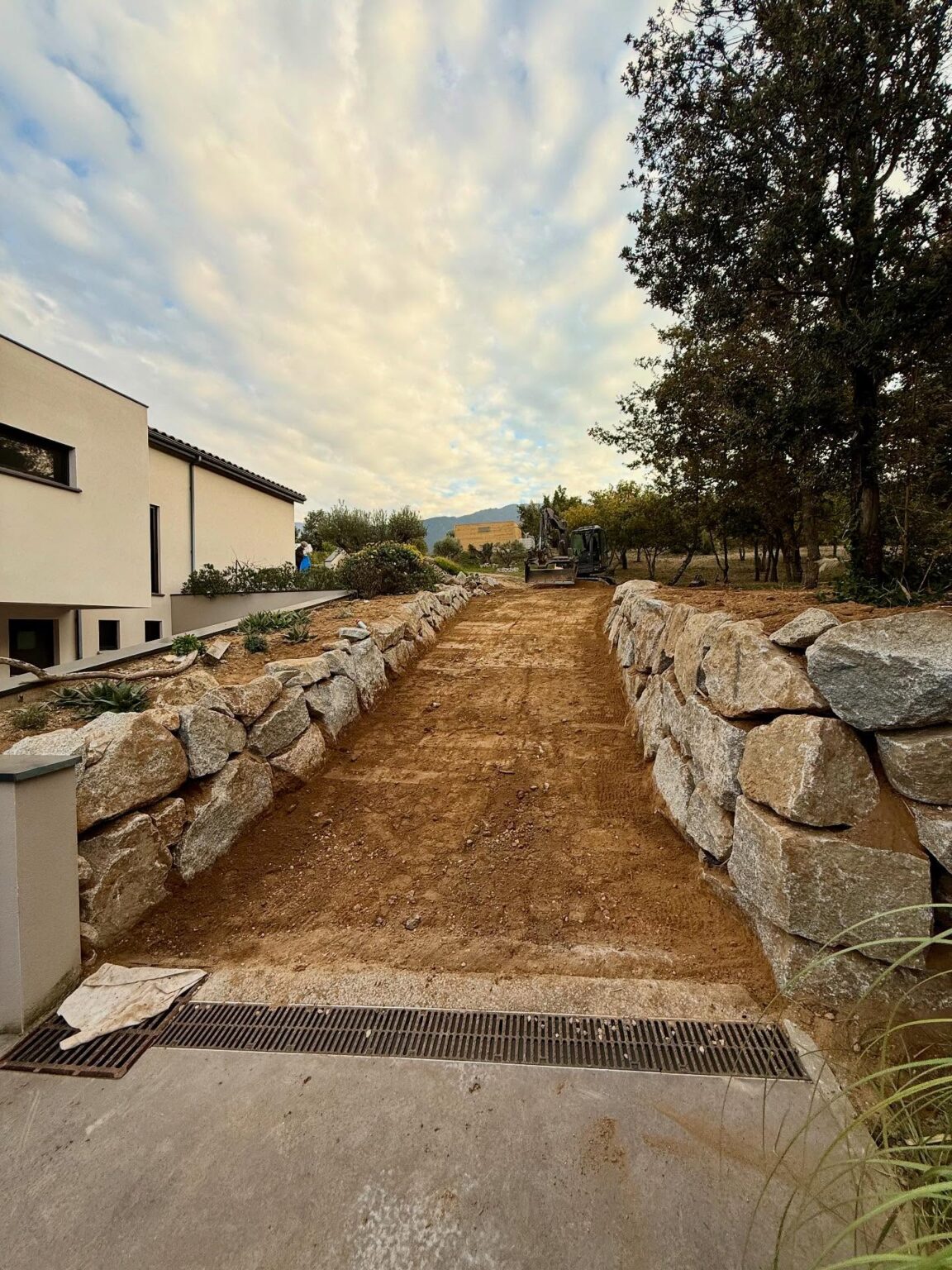 Chantier à Villelongue dels Monts : enrochement de type granite, réalisation d’un accès en enrobé avec bordures en schiste concassé, et création d’une aire de retournement en gravier granitique au fond de la parcelle.